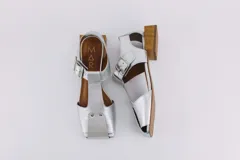 Sandalias de cuero negro con punta abierta y taco cuadrado de madera. Presentan tiras anchas en el empeine y ajuste con hebilla metálica.