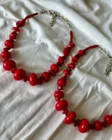Collar corto de cuentas rojas de diferentes tamaños y formas, con cierre ajustable.