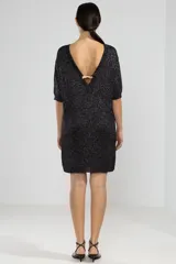 Vestido corto negro con brillos plateados, de tejido de punto con mangas 3/4 y corte recto.
