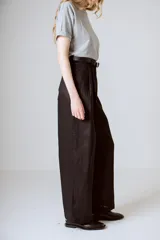 Pantalón negro de corte ancho y tiro alto, con pinzas en la cintura y bolsillos laterales.