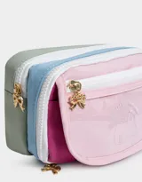 Cartuchera rectangular de tela estampada multicolor con divisiones internas, bolsillo frontal de PVC transparente con estampado de ositos y cierre con cremallera. Incluye un dije metálico con forma de moño.