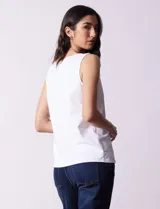 Blusa blanca sin mangas de seda fría, con cuello redondo y apliques de flores blancas.