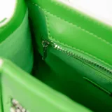 Cartera mini tipo tote, color blanco con detalles en verde manzana. Tiene doble asa corta y correa larga regulable y extraíble. Presenta un bolsillo frontal con cierre y logo XL en plateado.