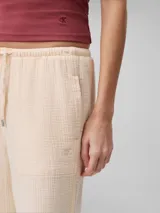 Pantalón de corte recto color beige, de gasa doble con textura arrugada, cintura elástica con cordón ajustable, bolsillos laterales y trasero.