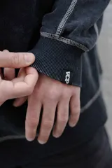 Buzo negro de frisa 100% algodón con calce oversize y lavado gastado. Presenta costuras a contratono, recortes y logos estampados en el frente y en el puño.