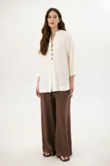 Sobrecamisa beige de corte recto, cuello mao y mangas 3/4. Presenta cierre frontal con botones de madera y bolsillos laterales.