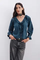 Camisa blanca de algodón con detalles de plumetí, puntillas, alforzas y bordados a tono. Tiene volados en el frente y mangas al codo abullonadas con elástico y volados.