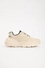 Zapatillas deportivas color beige con detalles en negro, de estilo chunky y suela track.