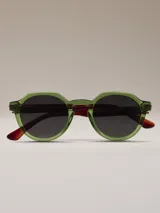 Lentes de sol con montura octogonal de acetato verde y patillas de acetato marrón con detalle naranja en el extremo. Lentes de color negro.