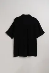 Camisa negra fluida de manga corta con cuello clásico y cierre frontal con botones.