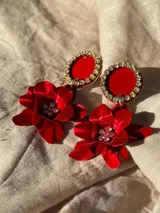 Par de aros colgantes con base circular negra con borde de strass y dije de flor negra con centro de strass.