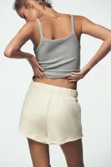 Shorts color crudo de tiro medio con cintura elástica ajustable con cordones y bajo desflecado.