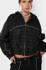Campera negra oversize con combinación de textil deportivo y sastrero, cierre metálico YKK desmontable, elástico en puños y cintura, vivo a contratono en mangas y cuerpo, forrada al tono.