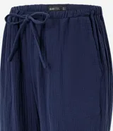 Pantalón femenino azul marino, estilo pijama, confeccionado en algodón texturizado. Posee cintura elástica con cordón para ajuste y bolsillos laterales.