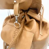 Mochila de cuero color camel con solapa con flecos y cierre con cordón de cuero.