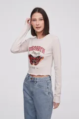 Remera de manga larga color beige con estampado gráfico de mariposa en el frente.