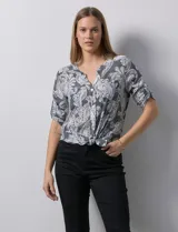 Blusa de gasa estampada en tonos grises y blancos, marca Ruby Rd. Tiene cuello a la base, escote en V y abertura con botones. Cuenta con bolsillos delanteros, mangas 3/4 regulables con presilla y botón, y terminación de ruedo con nudo.