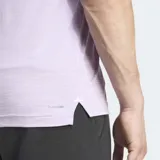 Remera de entrenamiento Adidas de corte ajustado, color lila jaspeado, con cuello redondo y logo de las tres barras en negro en el pecho.