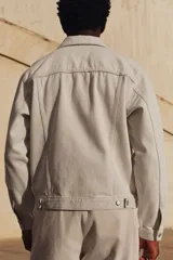 Campera de denim color crudo, de corte recto, con cuello clásico, cierre frontal con botones metálicos, bolsillos con solapa en el pecho y bolsillos laterales.