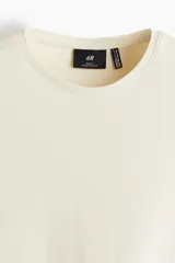 Remera color crema de punto liviano con cuello redondo ribeteado y bajo recto. Corte ajustado que realza el contorno del cuerpo creando una silueta entallada. Confeccionada con tejido funcional COOLMAX®, una fibra exclusiva de poliéster de secado rápido que elimina la humedad y regula la temperatura corporal proporcionando un ajuste cómodo y suave.