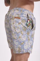 Short de baño para hombre, color azul oscuro con estampado floral o botánico en tonos rosados y celestes. Presenta cordón de ajuste blanco en la cintura.