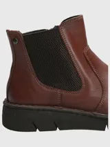 Botín de cuero color marrón con paneles elásticos laterales negros, diseño tipo Chelsea y suela de goma flexible negra con costuras decorativas visibles.