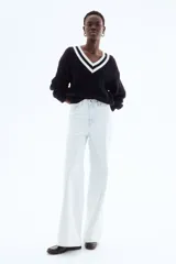 Pantalón jean celeste de denim de algodón rígido, corte ajustado de cintura a muslo y acampanado de rodilla a bajo, con cinco bolsillos, cierre y botón.
