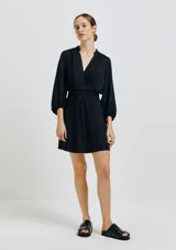 Vestido corto negro con escote en V, mangas largas abullonadas y cintura elastizada.