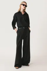 Camisa negra oversize de popelina de algodón, con cuello solapa, manga larga con puños abotonados, pinzas en la espalda y cierre frontal con botones.