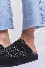Zueco negro con plataforma, tachas plateadas y hebilla ajustable.