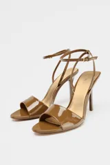 Sandalias color caramelo de charol con tira delantera, pulsera tobillera con hebilla y tacón fino alto.