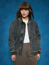 Campera de jean celeste con corte bomber, cierre frontal con botones metálicos, cuello redondo y puños y cintura acanalados.