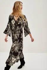 Vestido largo negro con estampado floral en color crema, escote en V y mangas acampanadas.