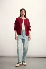 Chaqueta bomber negra con cierre frontal dorado y mangas largas con puños elásticos.