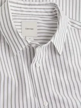 Camisa de popelín blanca con rayas verticales grises, corte regular, cuello inglés y cierre frontal con botones.