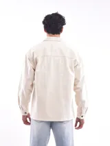 Campera gris oscuro de corte recto, con cuello clásico, cierre frontal con botones a presión, dos bolsillos de parche en el pecho con solapa y puños abotonados.