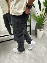 Pantalón de jean negro gastado, corte baggy con bolsillos cargo laterales.