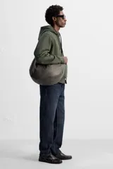 Bolso de hombro color marrón oscuro fabricado en piel con acabado craquelado. Tiene un compartimento principal con cierre de cremallera y un bolsillo interior con cremallera.