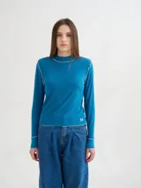 Polera negra de tela rib con cuello alto y mangas largas. Presenta pespuntes rojos en cuello, hombros y puños.