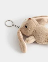Llavero con dije de conejo de peluche color beige, con cadena y aro metálico plateado.