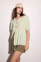 Blusa verde y blanca a rayas verticales, de calce holgado, escote en V con doble lazo ajustable, mangas 3/4 con volumen.