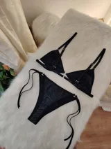 Conjunto de bikini negro con destellos verticales multicolor. El corpiño es de corte triangular con breteles finos regulables y aro metálico en el centro. La bombacha es tipo colaless con tiras laterales regulables.