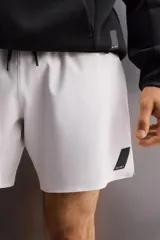 Shorts deportivos color verde oliva confeccionados en tejido técnico ligero y elástico. Cuenta con forro interior, cintura elástica ajustable con cordón, bolsillos laterales, bolsillo de seguridad en espalda con cierre de cremallera, bajo con aberturas laterales y logo estampado en la pierna.