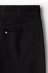 Pantalón de jean negro de corte holgado, tiro caído y piernas redondeadas extraamplias. Modelo de cinco bolsillos con cintura clásica y cierre frontal.