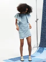 Vestido corto de jean celeste con volados en los hombros y ruedo desflecado.