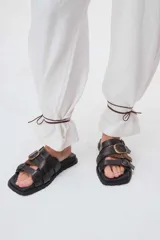 Sandalias de cuero marrón con tres tiras anchas y hebillas doradas.