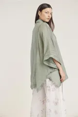 Camisa blanca de lino con corte amplio, cuello camisero y mangas 3/4 con detalle de puntilla en el borde.