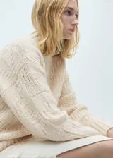 Sweater de punto grueso color crudo, con cuello perkins y diseño con bloques en relieve.