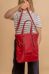 Cartera tipo tote bag color negro, con doble asa de mano y correa bandolera ajustable. Presenta un bolsillo rectangular en el frente.