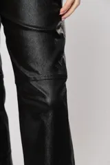 Pantalón de tiro alto negro de gabardina strech metalizada, con bolsillos y cierre frontal con cremallera y botón.
